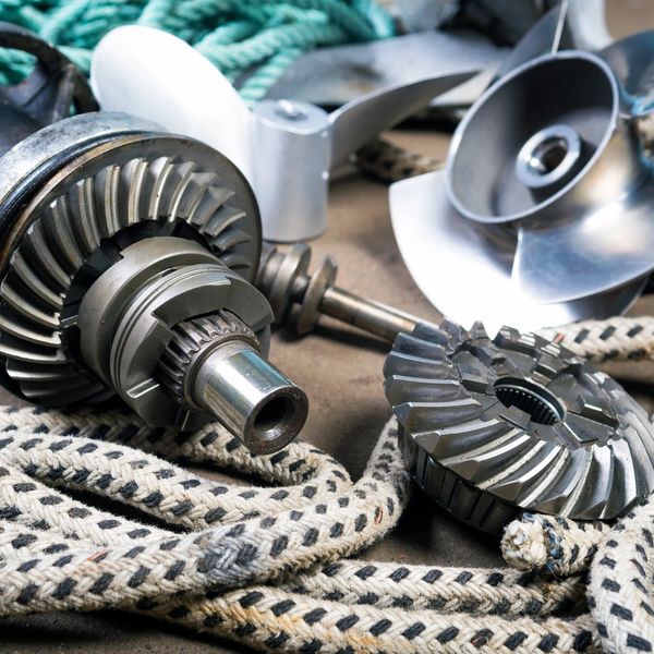 Close-up of metallic boat propeller parts and coiled ropes on the floor.