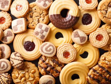 Assorted butter cookies with nuts, chocolate, and jam, arranged in a flat lay.