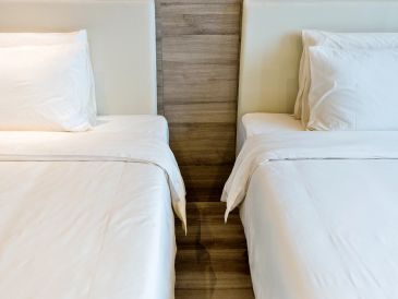 Two neatly made beds with white linens separated by a wooden divider.