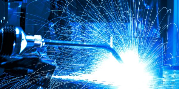 Bright blue sparks flying from welding metal in a workshop.