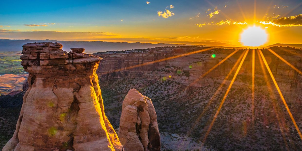 Sunrise over the Colorado National Monument wit the lush green Grand Valley below.