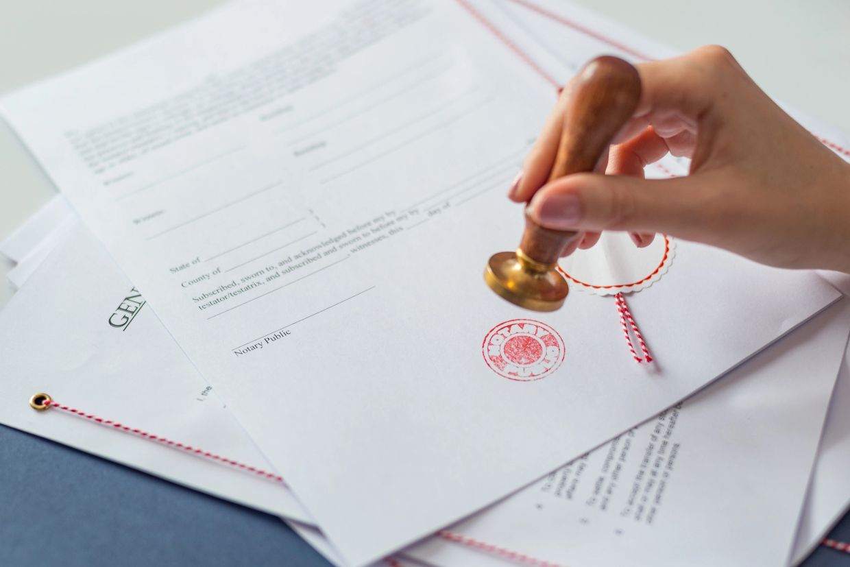 Hand stamping a document with a notary seal.