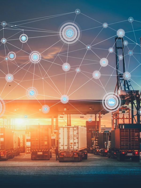 Trucks at a logistics hub with digital network overlay during sunset.