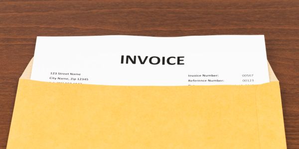 Invoice document partially inside a brown envelope.