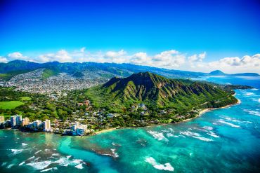 Aerial view of a coastal city with a volcanic crater and blue ocean.