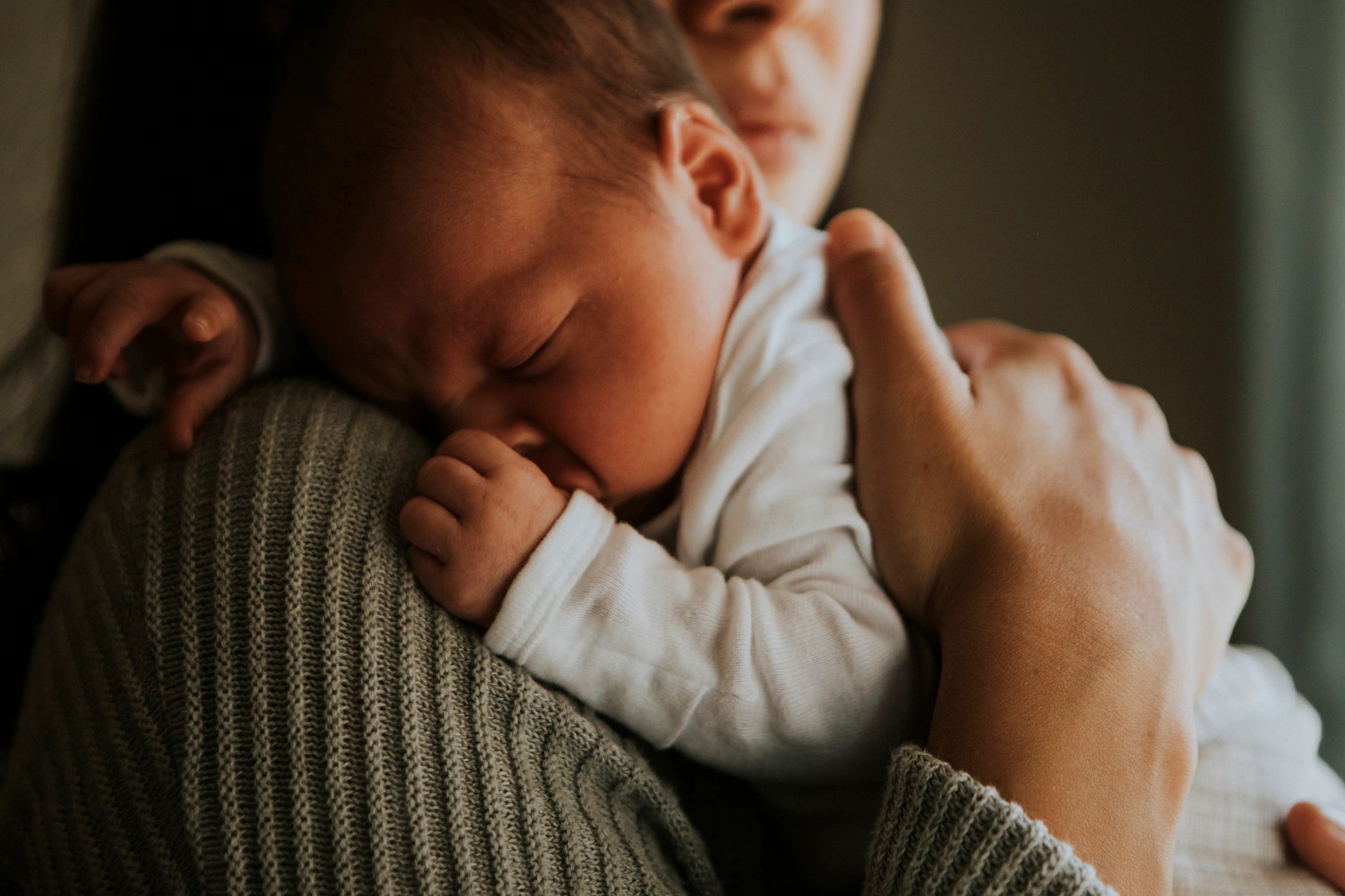Newborn baby resting on mother's shoulder.
