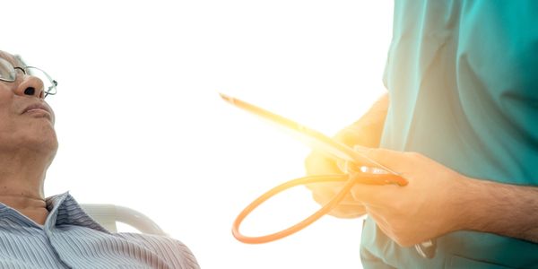 A healthcare professional holding a stethoscope near an elderly patient.
