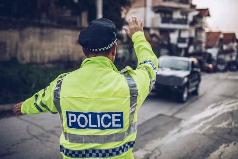 One man, traffic warden standing on the street, pulling car over for speed.