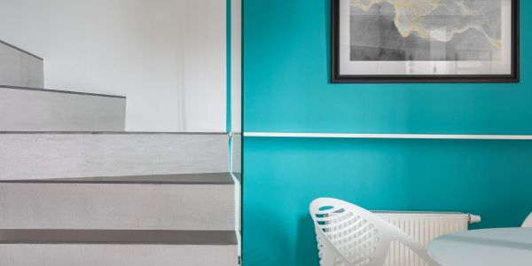 Minimalist interior with gray stairs and teal wall.