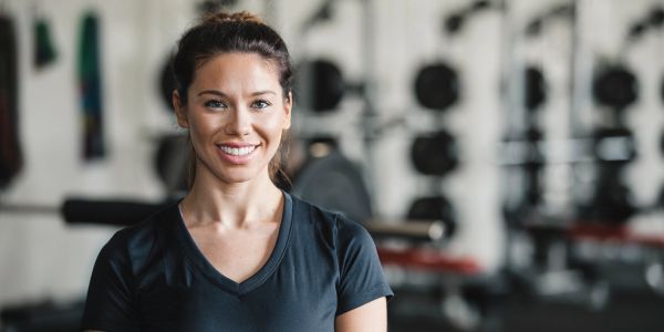 Smiling woman in black workout attire at the gym.