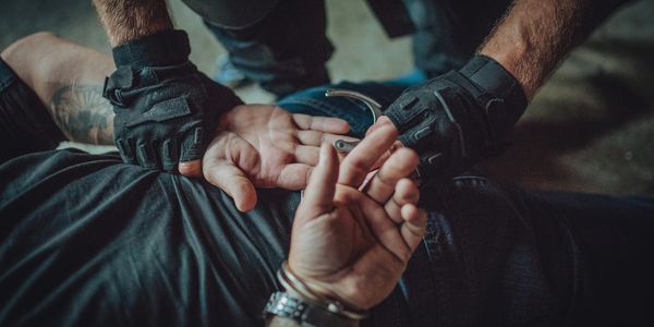 Officer handcuffing a person on the ground.