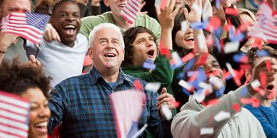 A diverse crowd enthusiastically waving American flags and celebrating.