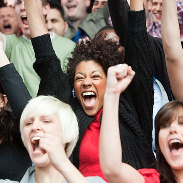 A diverse group of people cheering excitedly with raised arms.
