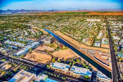 Aerial view of a city with a canal running through and mountains in the background.