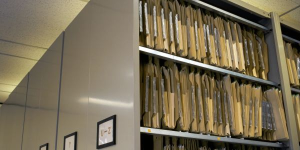 Shelves filled with organized hanging file folders labeled U-Z in an archive room.