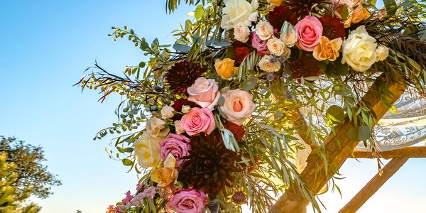 Colorful floral arrangement on a wooden arch during sunset.