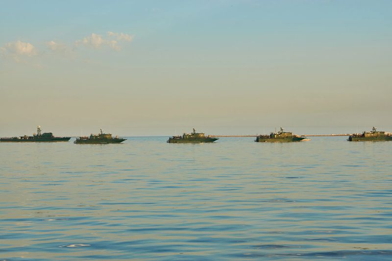 Military Battleships in a sea bay at sunset time. Modern warship sailing in still water. Coast Guard Ships guarding ocean