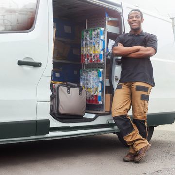 A delivery man stands by a white van loaded with packages.