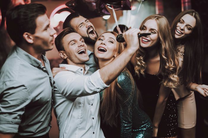 Group of friends singing karaoke and having fun at a party.