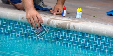 Person testing pool water with a color comparison chart.