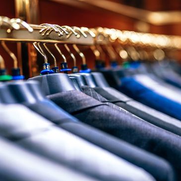 Close-up of men's suits hanging on a rack in a store.
