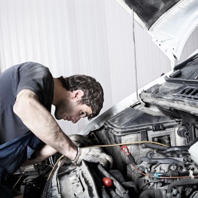 Mechanic inspecting a car engine with focused attention.