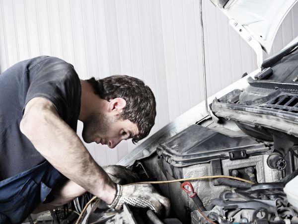 A mechanic closely inspects a car engine under the hood.