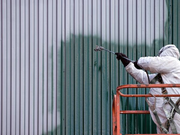Person spray painting a metal wall.