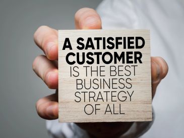 Sign reads 'A satisfied customer is the best business strategy of all.'