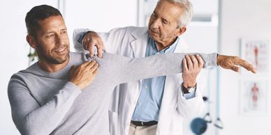 Doctor examining a patient's shoulder mobility in a bright clinic.