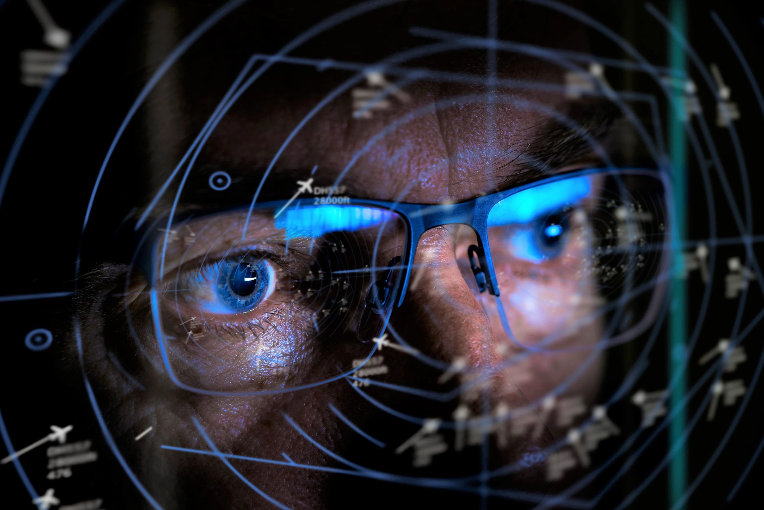 Close-up of a man with glasses analyzing flight radar data.