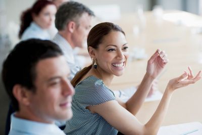 A woman smiling and engaging in a meeting with colleagues.