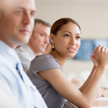 Three professionals attentively listening in a meeting.