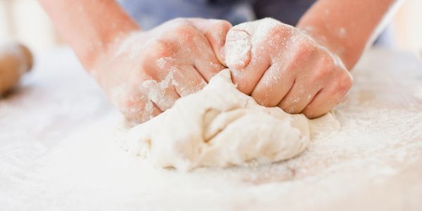 Hands kneading dough covered in flour.