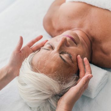 Elderly woman receiving a relaxing head massage.