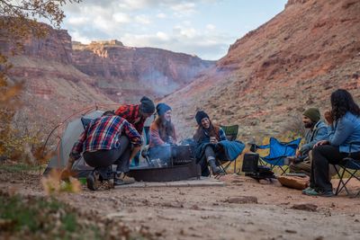 Group of friends enjoying camping by the campfire in a canyon.