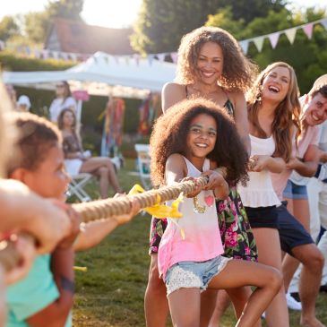 Group playing tug-of-war outdoors, smiling and enjoying.