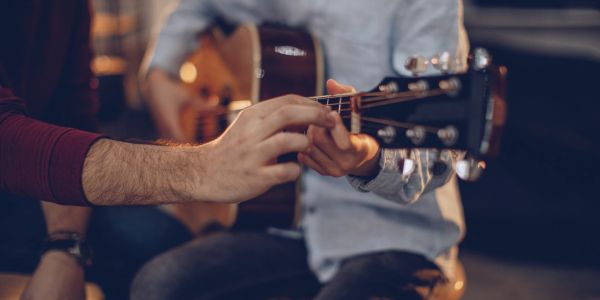 Two people tuning or playing guitars together.