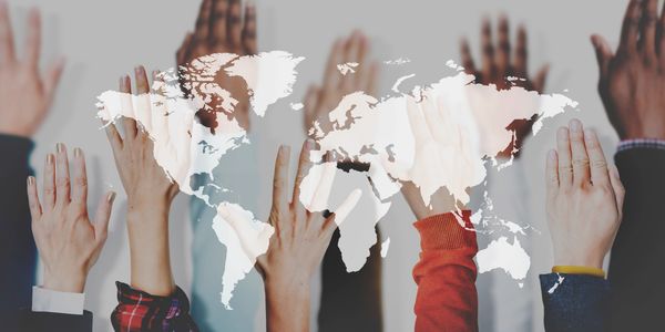 Diverse hands raised with a world map overlay symbolizing global unity.