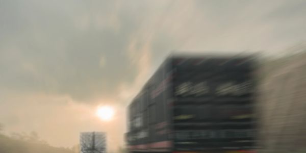 Blurred image of trucks driving on a highway during sunset.