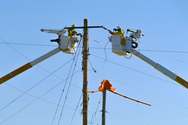 Linemen in bucket trucks working on electric power lines; dangerous occupations.