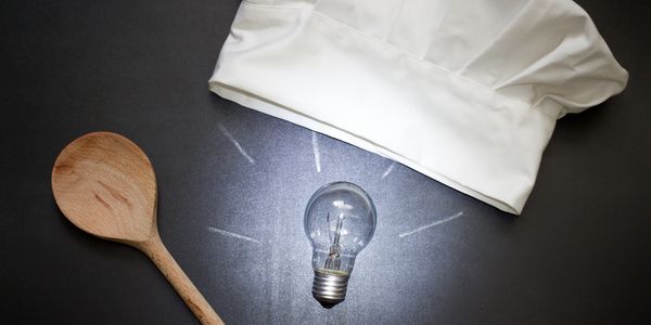 Chef hat, wooden spoon, and light bulb symbolizing culinary creativity.