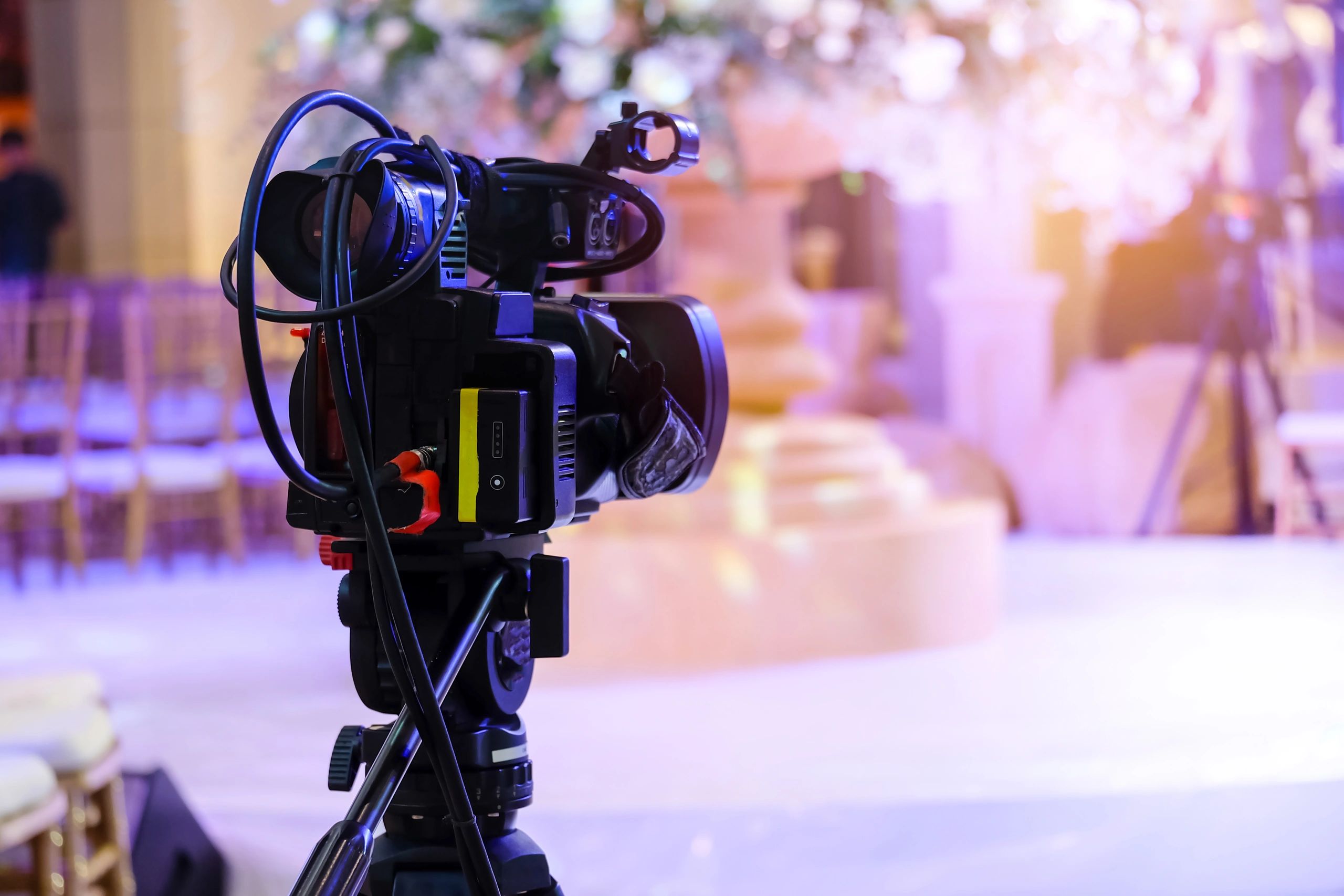 Professional video camera setup with purple and pink bokeh lighting.