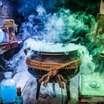Witch's cauldron with potion bottles and scrolls.
