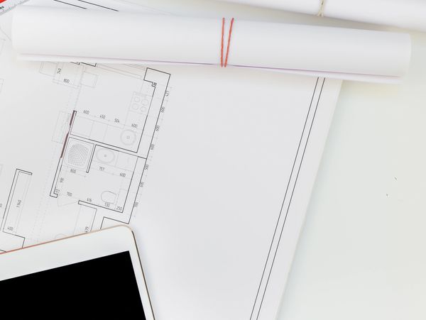 Rolled and flat architectural plans with a tablet.