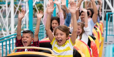 Children screaming with joy on a colorful roller coaster ride.