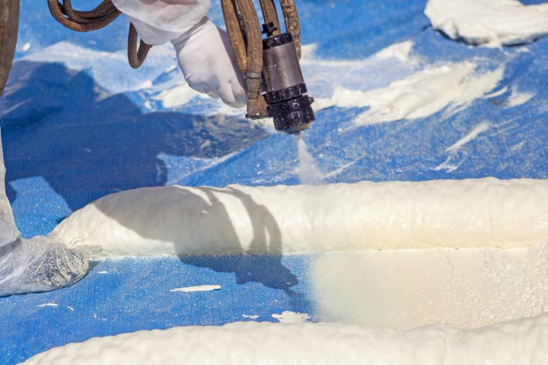 Technician dressed in a protective white uniform spraying foam insulation using Plural Component Spray Gun. Spraying polyurethane foam for roof and energy saving