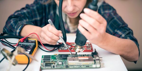 Person soldering electronic components on a circuit board.