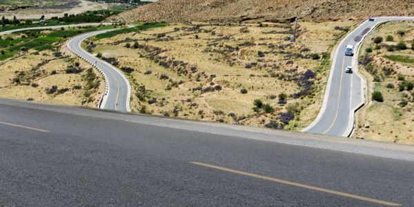 Winding mountain roads with sparse vegetation and distant snow-capped peaks.