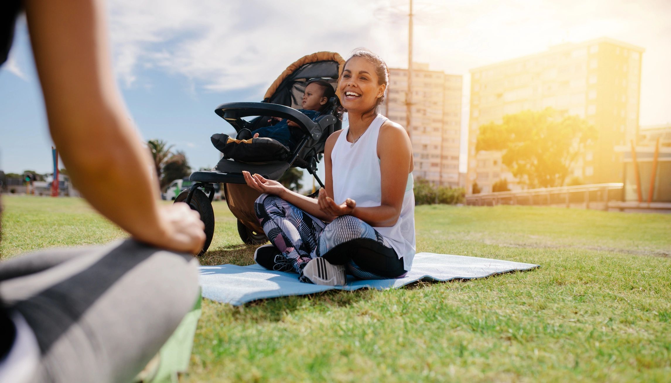 Woman chatting outdoors with baby stroller nearby.